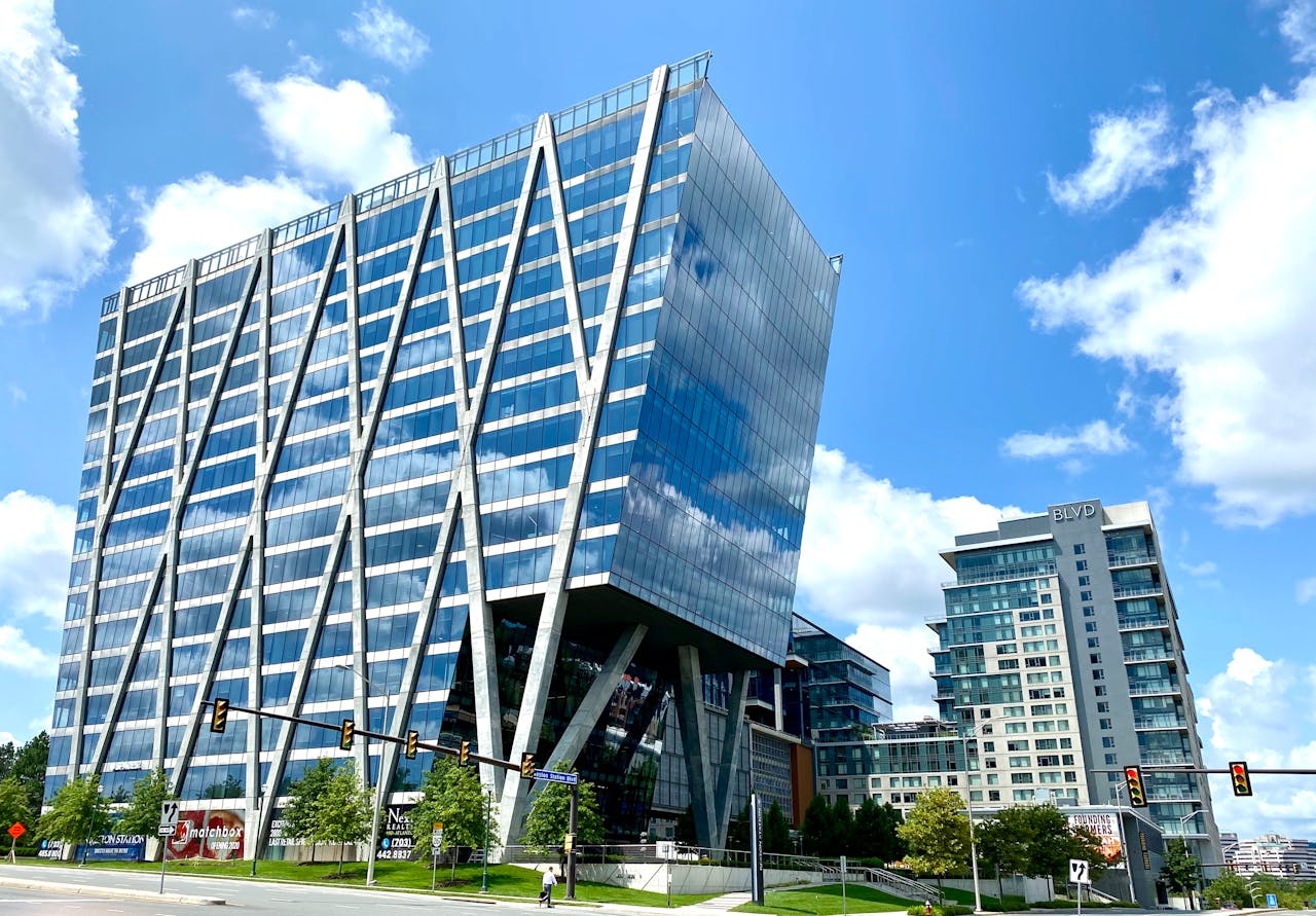 Tall modern office building with glass facade in an urban setting under a clear blue sky.
